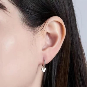 Close-up of minimalist S925 sterling silver heart-shaped drop hoop earrings on model