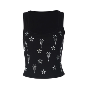 Détail du gilet en maille côtelée noire avec des fleurs en strass sur l'encolure carrée
