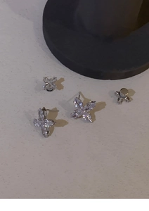 Detailed macro view of four silver butterfly stud earrings with sparkling zirconia stones