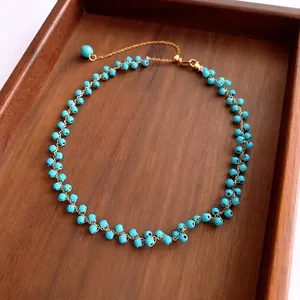 Collier bohème en perles de turquoise avec chaîne dorée et fermoir sur bois sombre