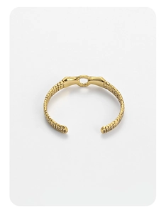 Detail shot of the golden snake skin texture and adjustable open cuff design on the bangle