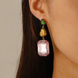 Close-up of dangling gold earrings with green, yellow and pink teardrop crystals on model