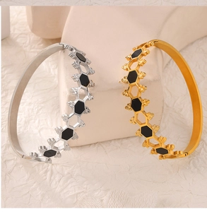 Detailed view of honeycomb patterned open bangles in gold and silver finish with black inlay