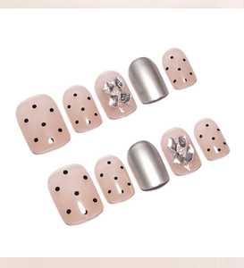 Detail view of nude press-on nails with silver glitter, black dots and mirror finish