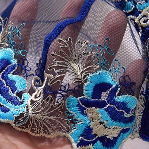 Detailed close-up of intricate blue floral embroidery on sheer mesh lingerie fabric