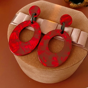 Nahaufnahme roter Marmor-Ohrringe mit schwarzen Metalldetails auf einer Schmuckbox