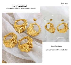 Detail of gold-plated irregular lava textured earrings on white fabric and glass