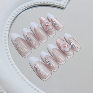Pink cat eye almond press-on nails with 3D floral accents and elegant French tips