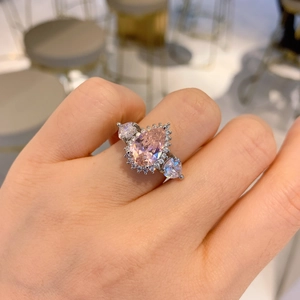 Silver ring featuring a pear-cut pink gemstone with heart-shaped side zircons on hand