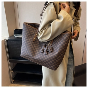 Detail of large brown monogram tote bag with leather handles and cute elephant charm