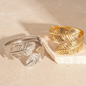 Gold and silver metal leaf-shaped open bangles on stone and marble texture background