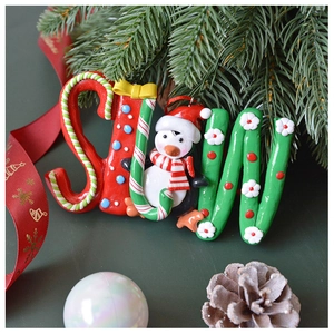 Detailed view of red and green SNOW letter ornament with penguin and candy cane motifs