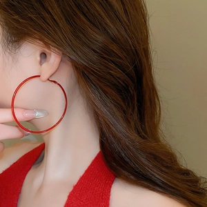 Close-up of elegant large red hoop earrings on a model with warm tones