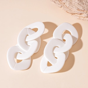Boucles d'oreilles créoles blanches en acrylique avec maillons sur fond beige