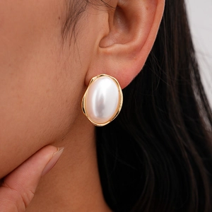 Gros plan d'une boucle d'oreille baroque avec grande perle ovale et bordure dorée