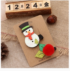 Close-up of snowman and pom-pom Christmas hair clips on a natural card with pine cones