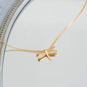 Dettaglio macro del ciondolo a libellula dorata con pavé di zirconi bianchi luminosi