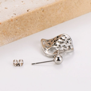 Detail eines silbernen Herz-Ohrrings in Fächerform mit metallischem Glanz auf Stein