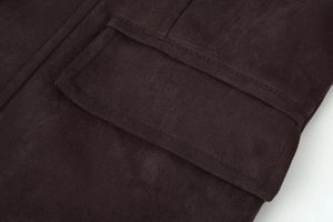 Gros plan détaillé de la veste en daim marron foncé avec coutures précises sur la poche