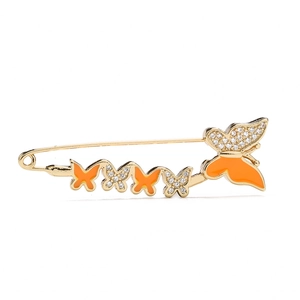 Detail view of gold butterfly safety pin brooch with orange enamel and crystal rhinestones