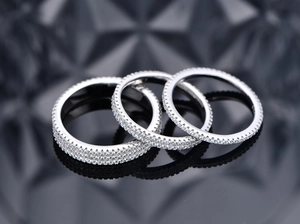 Close-up of three 925 sterling silver rings with micro-pave white stones on dark surface