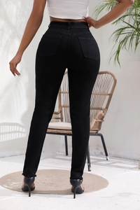 Détail d'un jean slim noir montrant l'ourlet effiloché et les poches arrière sur mannequin