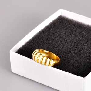 Detailed view of vintage gold-plated ring with white enamel stripes on a display box
