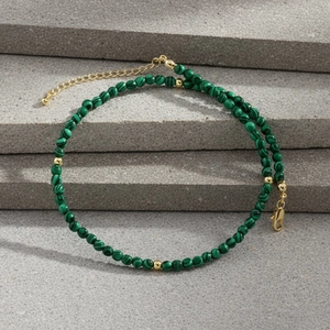 Macro view of malachite beaded necklace with gold metal spacers on stone surface