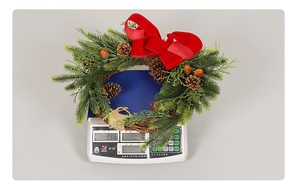 Detailed top view of Christmas wreath weighing 398g on a digital scale for size reference
