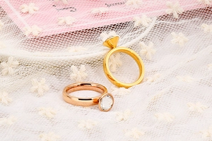 Primo piano di anelli in acciaio oro e rosa con grandi pietre di zircone trasparente