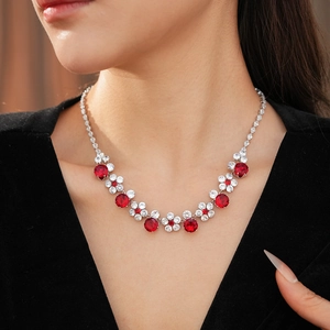 Close-up of luxury red zircon flower necklace worn by a model on a black background