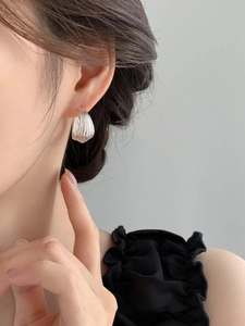 Close-up of a silver multi-layer curved earring worn by a model in a modern style