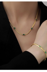 Dettaglio del set collana e bracciale a catena serpente dorata con zirconi verde smeraldo