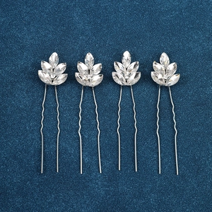 Macro detail of silver leaf crystal bridal hair pins set on navy textured fabric