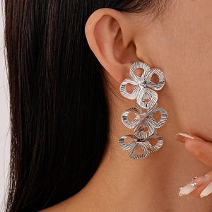 Close-up of triple-layered silver floral tassel earrings with textured finish on a model