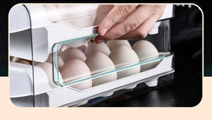 Detail of hand pulling drawer on white double-layer transparent plastic egg storage box