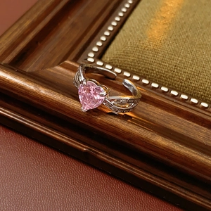 Close-up of pink heart-shaped gemstone ring with micro-pave diamonds on vintage wood