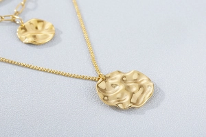 Detailed view of layered gold necklace featuring textured circular pendants on fine chains