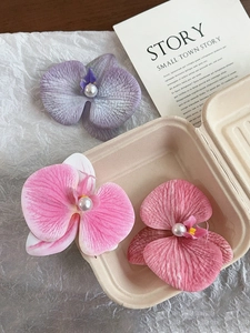 Macro detail of orchid hair clips featuring silk texture and center pearl accents