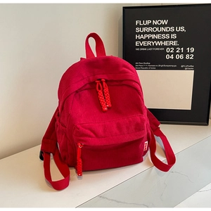 Detail of red corduroy mini backpack on marble surface with front zipper pocket