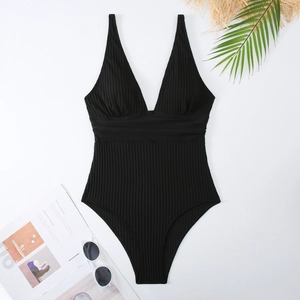 Dettagli in piano del costume intero nero a coste con scollo a V e accessori da mare