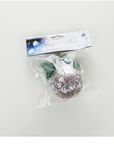 Close-up of a silver glitter Christmas ball with pine needles and red berries packaging