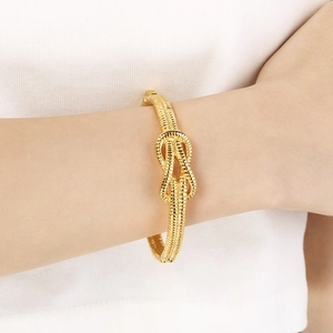 Close-up of a minimalist gold knot cuff bracelet worn on a wrist for a stylish look