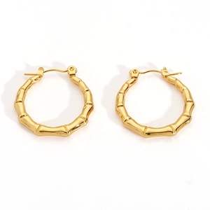 Macro detail of gold bamboo-shaped hoop earrings with polished texture and secure clasp