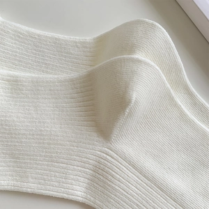 Macro shot of white ribbed knit socks with detailed heel stitching and soft cotton texture