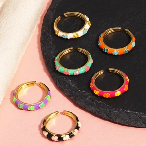 Detail of multi-colored enamel heart open rings in gold plating on dark stone