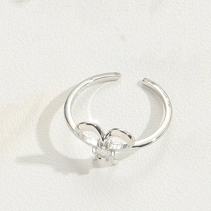 Detail of silver bow ring with small diamond accents and adjustable open band design