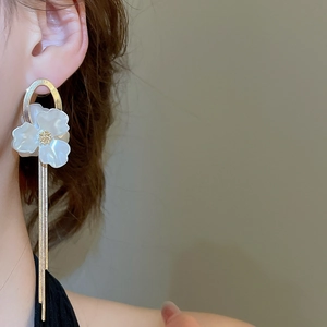 Detail showing long tassel earrings with white flower petals and golden metal chains