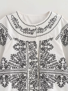Gros plan sur la broderie noire complexe sur la veste en coton et lin blanc de qualité