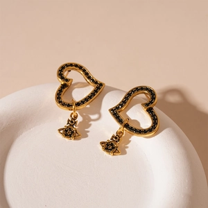 Detail of vintage gold heart earrings with black zircon stones and iconic orb pendant